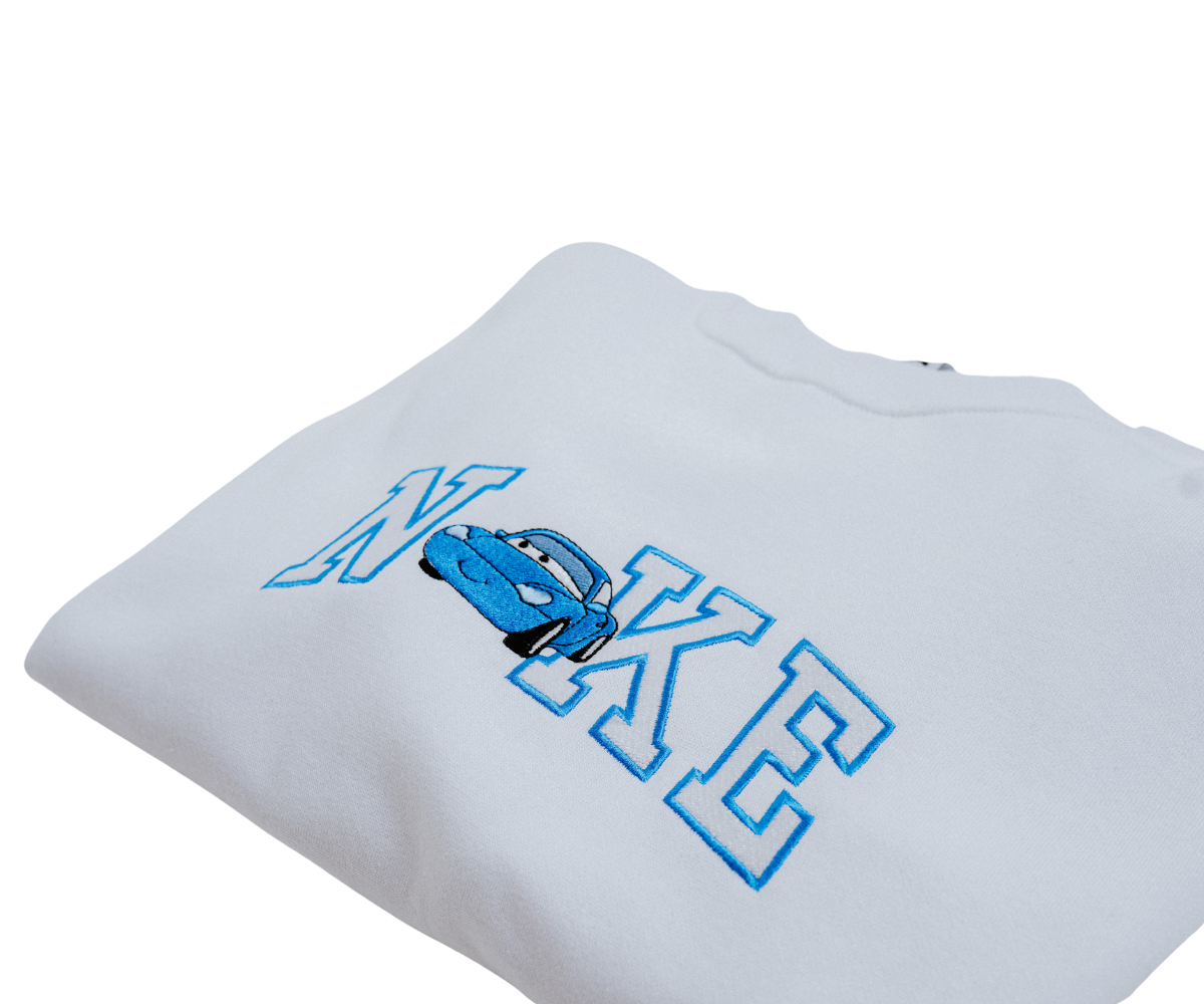 Fehér pulóver kék "NIKE" felirattal és egy rajzfilmautóval.