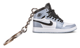 Kulcstartó Jordan 1 Smoke Grey cipő formájában fekete fűzőkkel.