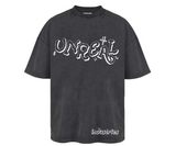 Washed black t-shirt with white "UNREAL" graphic and "industries" text.