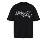 Fekete UNREAL feliratú póló.